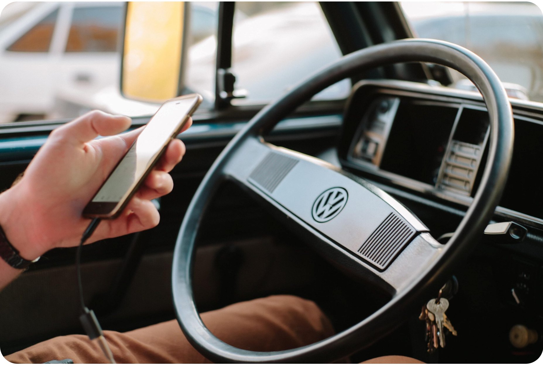 A driver holding a phone at the wheel of a Volkswagen